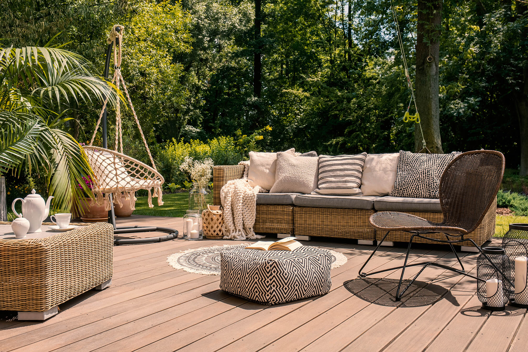 Auf einem Holzdeck im Garten stehen gemütliche Gartenmöbel im Flechtdesign 