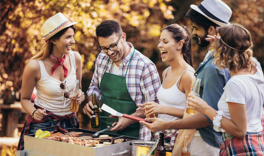 Freunde, die lachend um einen Grill herumstehen