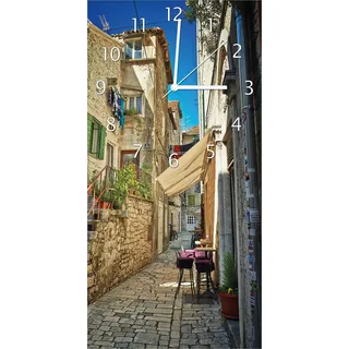Wallario Design Wanduhr Romantische Gasse in Kroatien mitten in der Stadt aus Echtglas, Größe 30 x 60 cm - Gelb